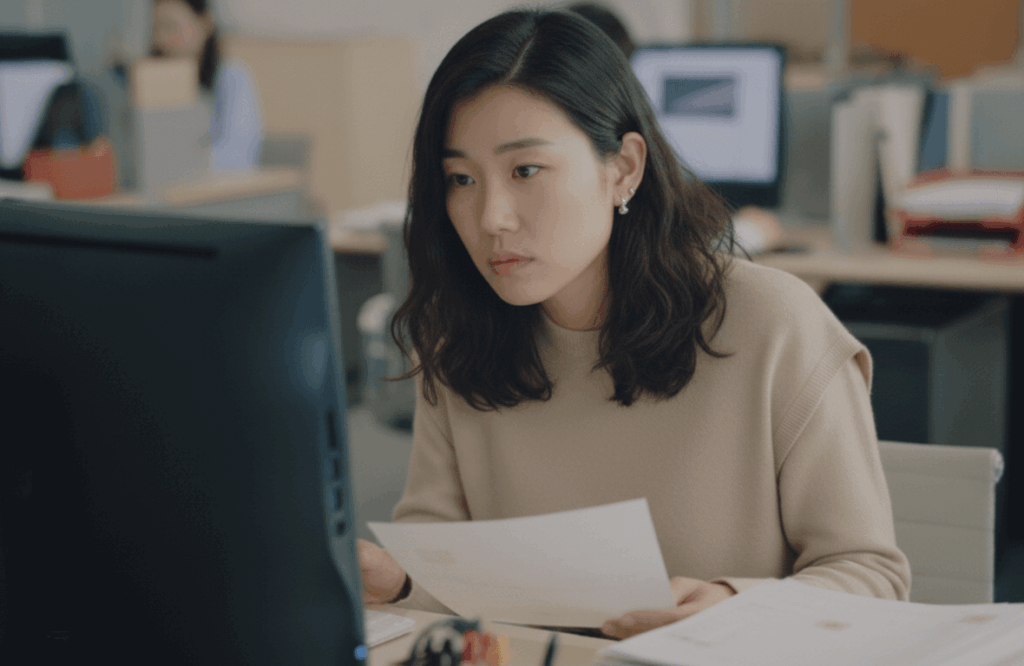 紙を見ながらPCを入力する女性